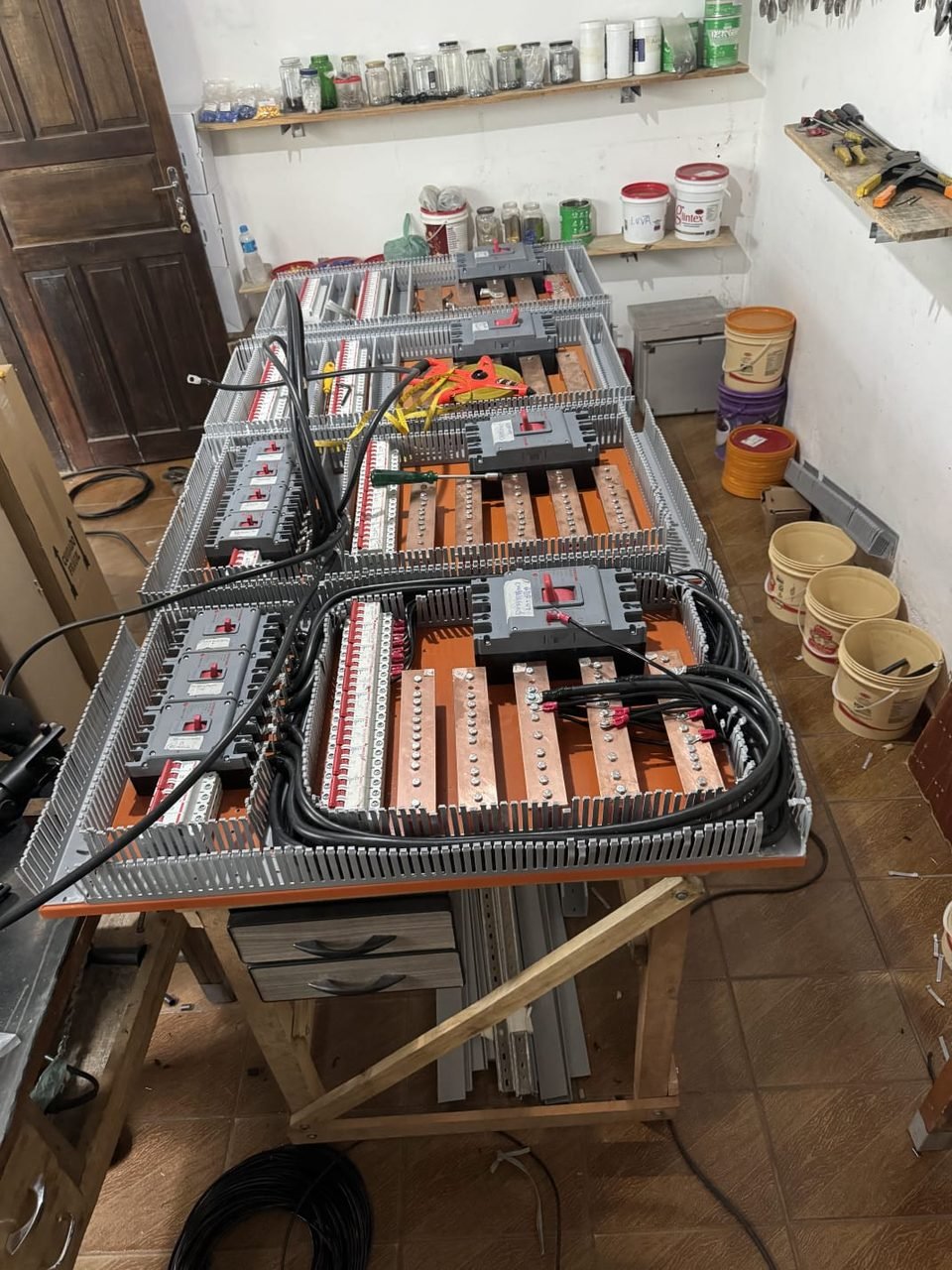 Painéis elétricos industriais em montagem na bancada da oficina da Maxtec, com barramento de cobre e disjuntores